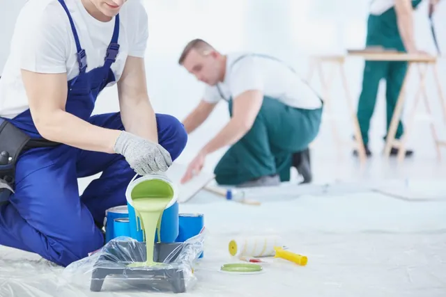 Person streicht eine Wand mit grüner Farbe
